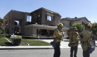 Bomberos frente a casa afectada por el incendio en California