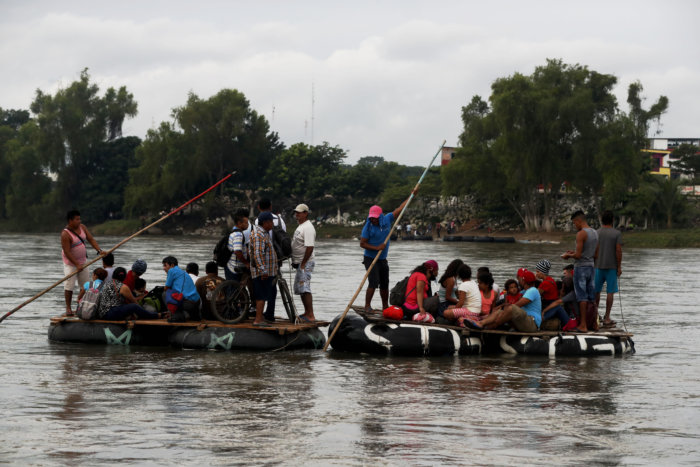 Migrantes hondureños cruzan en balsa el río fronterizo de Guatemala y México
